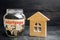 Glass jar with coins and the inscription `mortgage` and a small wooden house. credit for property / apartment. Business loans for