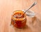 Glass jar  of cream  caramel sauce with sea salt pieces and spoon inside close-up on wooden background