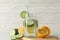 Glass jar of cucumber water, slices and lemons on background, close up