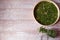 Glass jar and dehydrator grid with dried spring green onion feathers on a light wooden background.