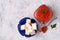 A glass jar filled to the top with red caviar with a plate with pieces of butter, a spoon with red caviar and herbs next to it