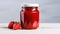 a glass jar filled with vibrant strawberry jam on a clean, white wooden surface to emphasize the freshness and