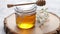 Glass jar full of fresh honey placed on slice of wood