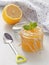 Glass jar full of lemon curd with cute spoon upon rustic table. Vertical.