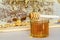 Glass jar of honey with wooden dipper on background of frame with honeycombs.