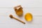 Glass jar of honey with wooden drizzler on colored background. Honey pot and dipper high above. Top view copy space