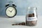 Glass jar with label PENSION and coins near alarm clock