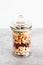 Glass jar of mixed nuts including almonds cashews and pistachios, natural healthy pantry ingredients