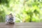 Glass jar with money and word SAVINGS on table against blurred background