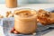 Glass jar with peanut butter, peanut, kitchen towel, spoon and peanut butter sandwich on white wooden background