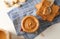 Glass jar with peanut butter, peanut, kitchen towel, spoon and peanut butter sandwich on white wooden background