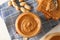 Glass jar with peanut butter, peanut, kitchen towel, spoon and peanut butter sandwich on white wooden background, top view