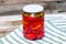 Glass jar with pickled red bell peppers.Preserved food concept, canned vegetables isolated in a rustic composition