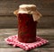 Glass jar with pickled rolled up red chili peppers on a wooden background