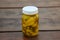 Glass jar of pickled yellow jalapeno peppers on wooden table