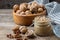 Glass jar of raw organic walnut butter and fresh nuts in bowl on table.