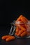 Glass jar with small peeled pieces of carrot on dark textured backdrop