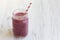 Glass jar with smoothie made of banana, black currant, coconut milk on a white wooden table, side view