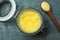 Glass jar and spoon of Ghee butter on light blue wooden table, flat lay