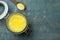 Glass jar and spoon of Ghee butter on light blue wooden table, flat lay. Space for text