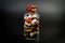 Glass jar with sweets closed by a cork and sealed with sealing wax shot on a dark background