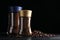 Glass jars with aromatic instant and ground coffee near beans on black wooden table. Space for text