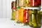 Glass jars with different pickled foods on wooden background, closeup