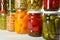 Glass jars with different pickled foods on wooden background, closeup