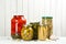 Glass jars with different pickled vegetables on white background