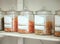 Glass jars of different types of pasta lined up in a row on a display shelf in a grocery store. Get to the local grocer