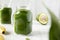 Glass jars full of green smoothie with spinach, avocado and banana, side view. Close-up