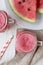 Glass jars full of watermelon smoothie with fresh slices of water melon, top view. White wooden background. Flat lay