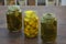 Glass jars of pickled green and yellow jalapeno peppers on wooden table