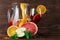 A glass jug of beverage with slices of apple and oranges, a grapefruit and green leaves of mint on a wooden background.