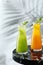 Glass jug of fresh lemonade on marble table and light background with shadow of tropic branch