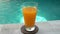 Glass of juice amid water on edge of swimming pool in tropical resort