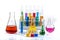 Glass laboratory materials such as erlenmeyer, tubes, and measuring cylinder containing colored liquids.Science chemistry concept