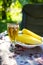 A glass of light beer in a glass along with a plate of boiled corn  standing on the table. Summer picnic  outdoor recreation
