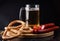 Glass of light beer, meat sausages and tomatoes on wooden board