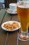 Glass with light beer, roasted peanuts and a cup of americano on a wooden table. Soft focus