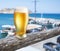 Glass of light beer on the seaside bar counter. Boats in the doc