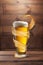 Glass of light fresh beer with flying spiral splash around mug.