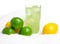 Glass of lime juice with ice cubes,limes,lemons on snow on white