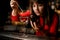 glass with liquid stands on bar and female bartender adds ingredient to it