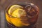 Glass of Long Island iced tea with lemon slice and straw. Close-up of an amber-colored alcoholic drink with ice on table in a bar