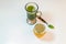 Glass of macha green tea with green tea powder in a spoon and small bottle of honey on white background