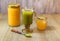 Glass of macha green tea with green tea powder in a spoon and two bottle of honey