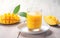 Glass mango juice and mango slices for healthy breakfast on white wooden table