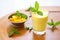 glass of mango lassi surrounded by fresh mangoes and mint leaves