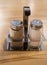 Glass and metal salt and pepper shaker set on wooden table in cafe, close up, vertical frame